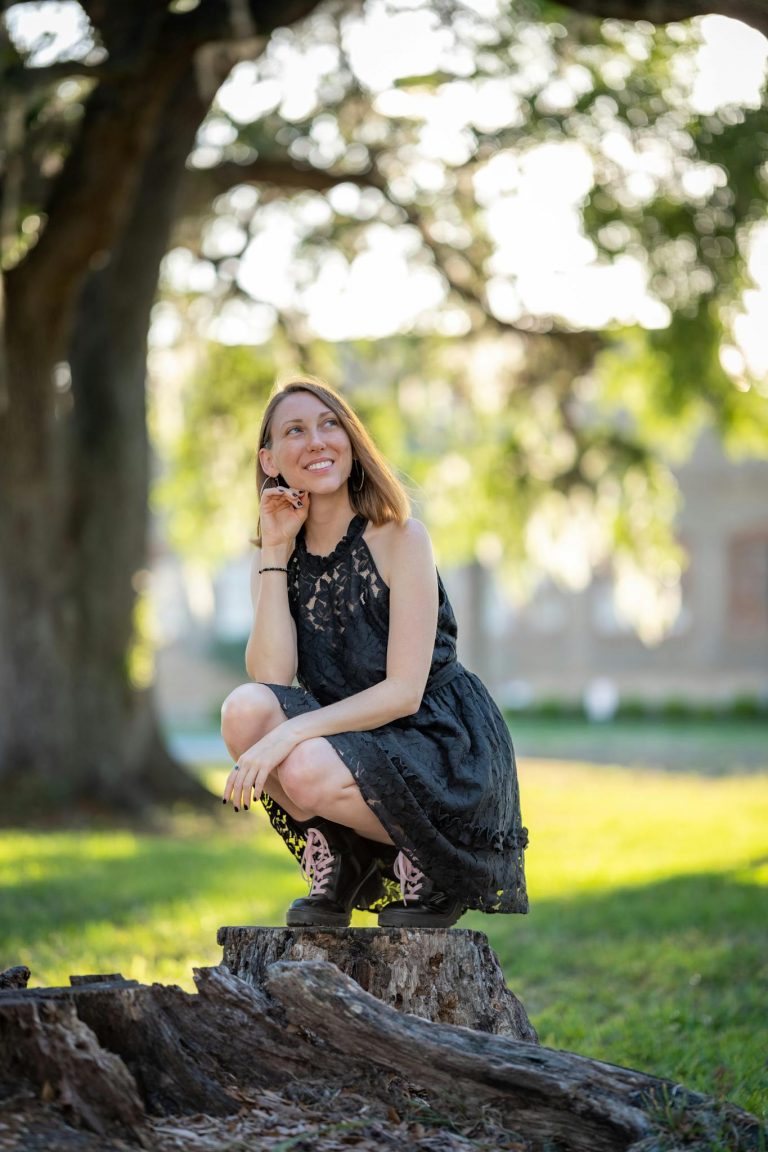 A woman in black dress sitting on a stump