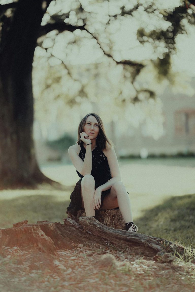 A woman sitting on a tree stump in front of a tree